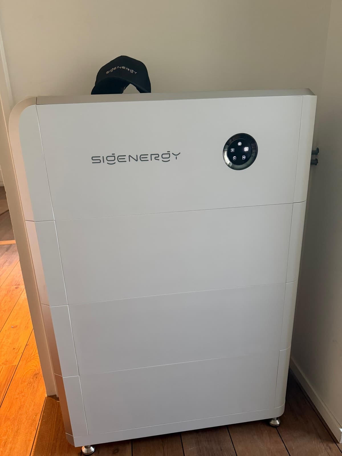 SigenStor-thuisbatterij binnen op een houten vloer tegen een lichte wand