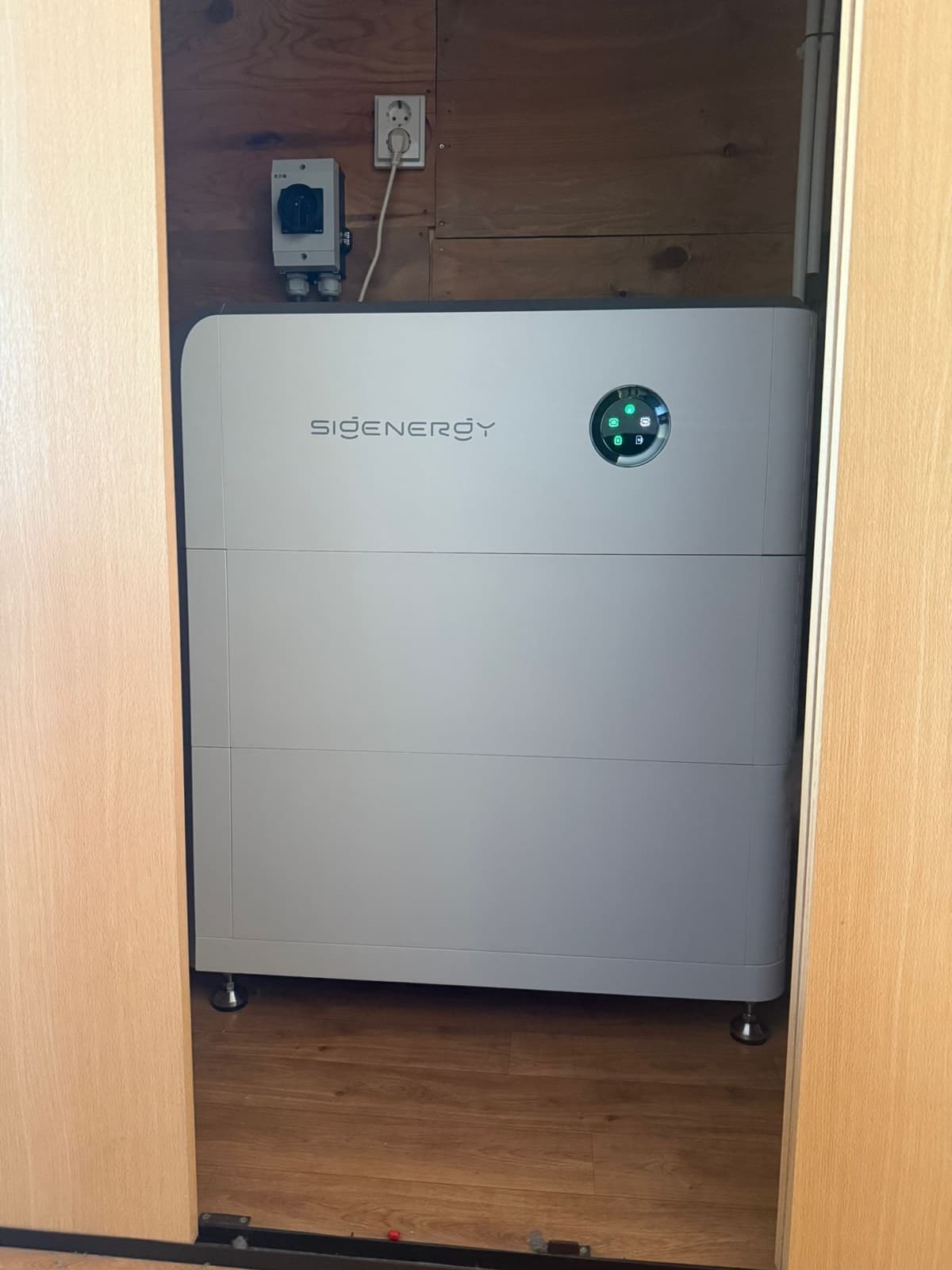 SigenStor-thuisbatterij weggewerkt in een inbouwkast met houten deuren